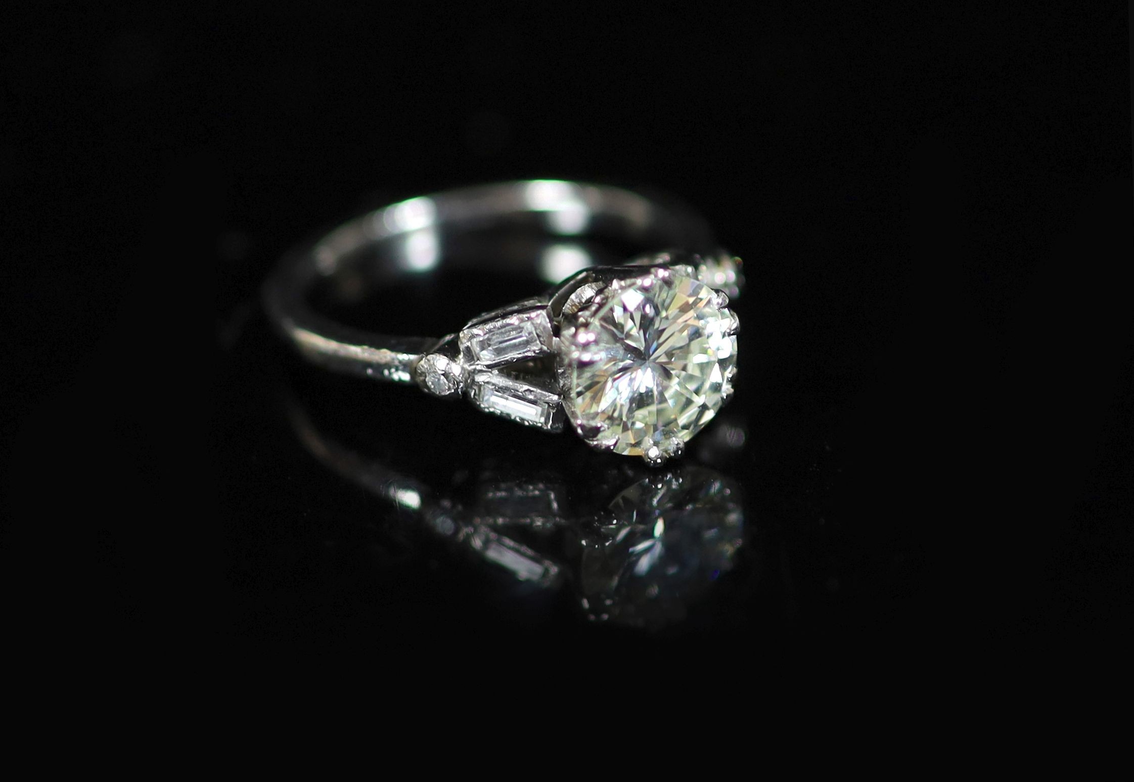 A platinum and single stone diamond ring, with baguette and diamond chip set shoulders